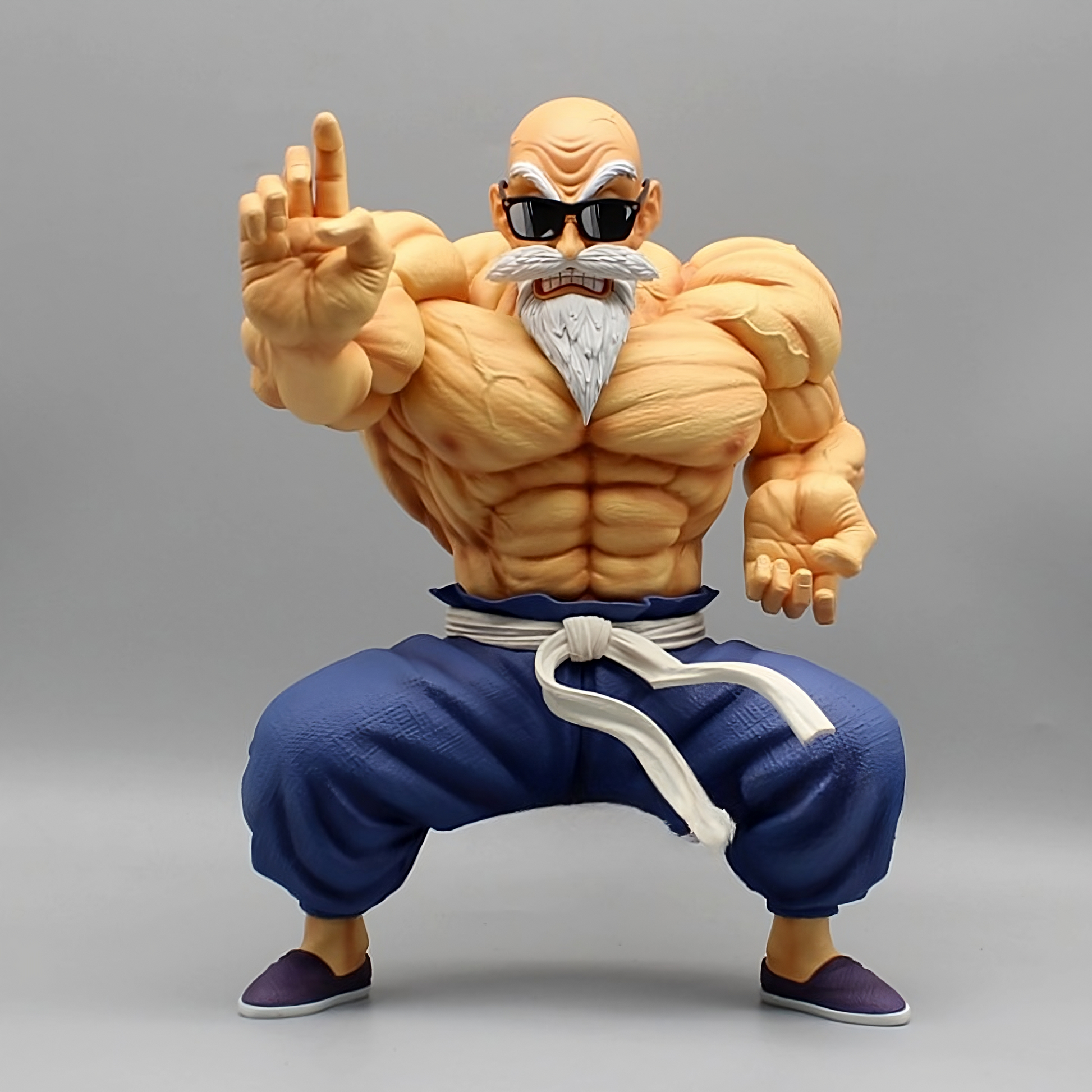 Master Roshi in his muscular form as a Dragon Ball collectible figure, wearing sunglasses, a blue martial arts uniform, and posing with an extended hand.