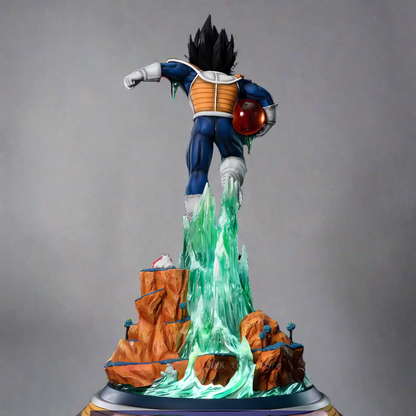 In this rear view of the Energy Blast Vegeta collectible figure from Dragon Ball Z, Vegeta stands powerfully atop a rocky structure with water cascading around him, gripping a glossy four-star Dragon Ball. The figure is set against a dark background, focusing on the character's muscular silhouette and the translucent water's sculpted motion, grounded by the DRAGON BALL Z logo base.