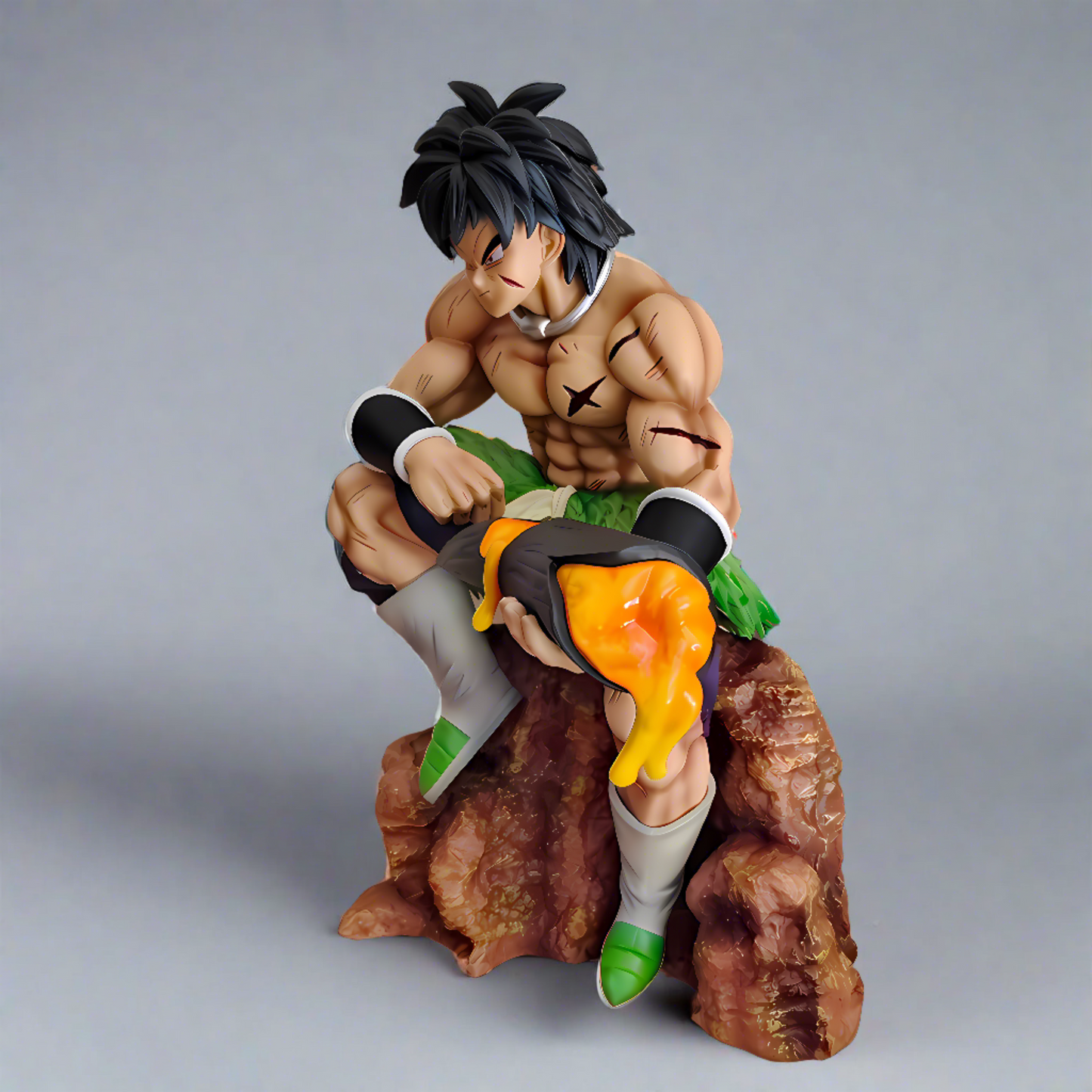 Broly Dragon Ball action figure with intense gaze, seated on a rock and holding a molten lava book, against a dynamic background of embers and flames.