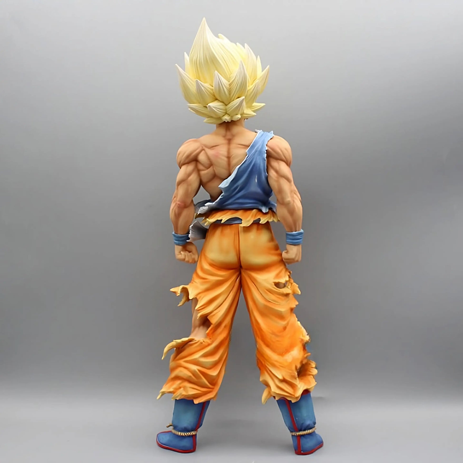 Rear view of the 'Ascend to Saiyan Glory Goku' figure from Dragon Ball, featuring Goku in Super Saiyan form with spiky golden hair and detailed muscular back. His iconic orange gi is tattered, flaring out at the bottom, and his blue sash billows to the side, emphasizing the energy of transformation, all set against a plain background to highlight the figure's details.