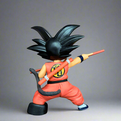 Back view of the young Goku collectible figure from Dragon Ball, showcasing the 'Turtle School' uniform and Power Pole, against a vivid sky and fire, highlighting the origins of the Dragon Ball saga.
