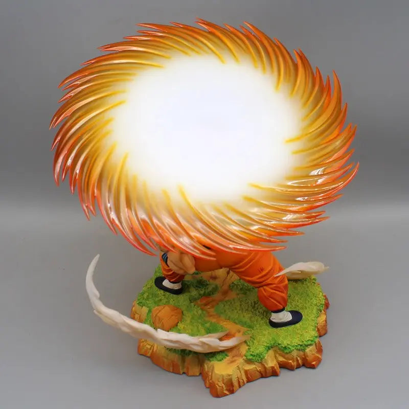 Aerial view of a Dragon Ball anime PVC statue showing Krillin from above, unleashing a glowing Destructo Disc that dominates the scene with its fiery orange and yellow hues, over a textured base simulating rugged terrain and vibrant greenery.