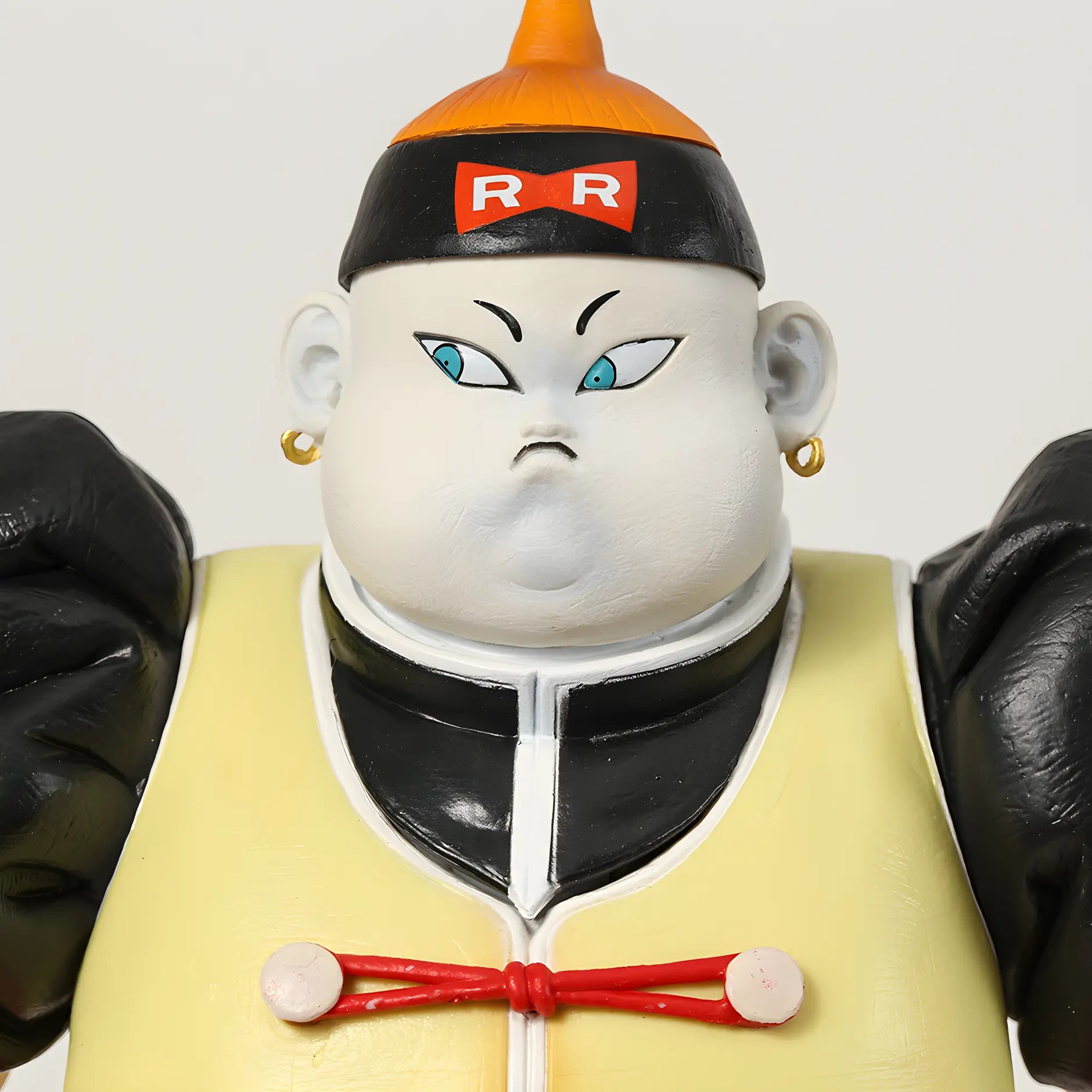 Close-up of Android 19's face from the Dragon Ball collectible series, featuring blue eyes and a calm expression, adorned with a Red Ribbon Army cap.